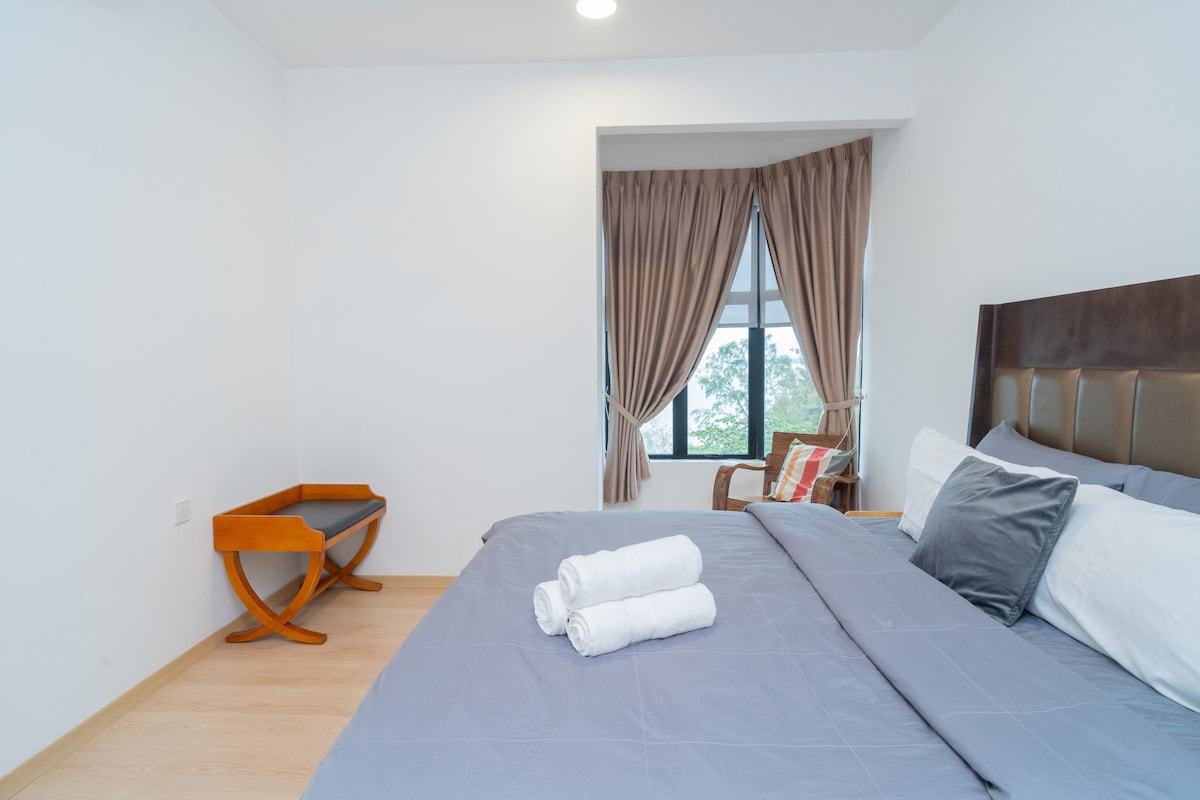 Spálňa 2 (8. poschodie) má manželskú posteľ s chladnou sivou posteľnou bielizňou a čalúneným čelom. Okno do zálivu prináša prirodzené svetlo a zeleň, zatiaľ čo teplé akcenty, ako je ratanová stolička a lavička, dodávajú útulný nádych.
