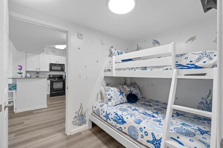 The sea-inspired guest en-suite features a Twin over Full bunk bed and a stunning walk-in tile shower. The kids will enjoy their own coastal retreat, complete with a flat-screen TV for entertainment.