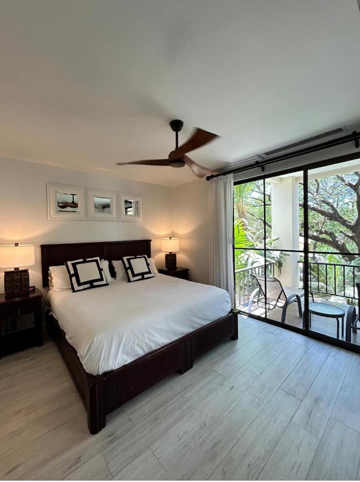 Главна спална соба со прошетка до терасата со поглед кон базенот и градините.