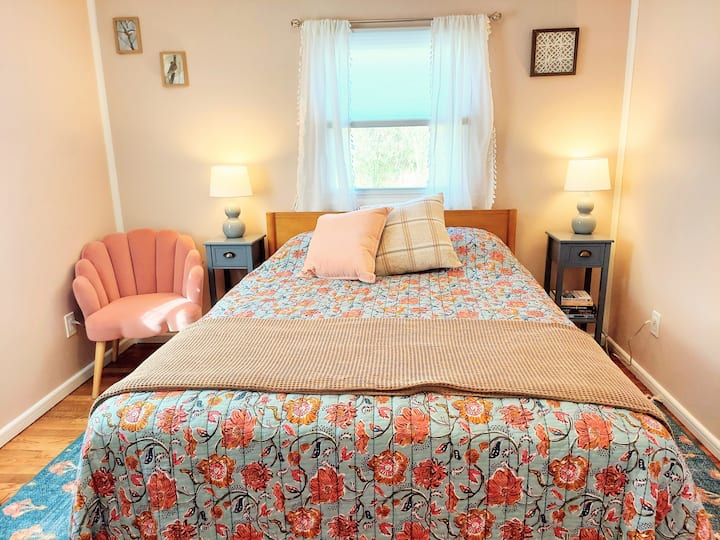 בחדר השינה הראשי יש מיטת קווין סייז מעץ מלא ומצעים פרחוניים יפים.