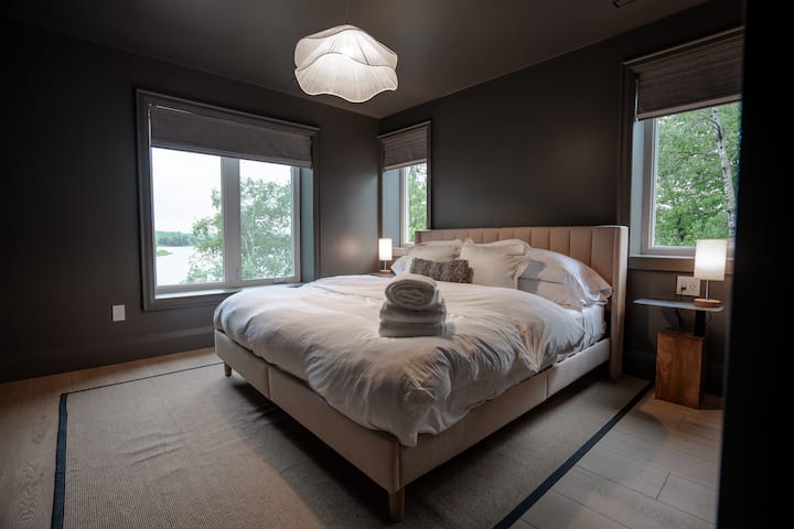 King sized bed in a dark themed room featuring a closet. 