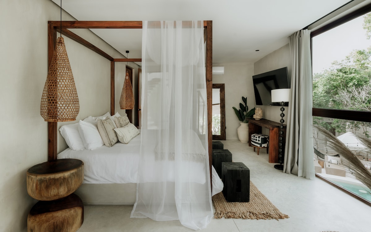 The king-size canopy bed is the centerpiece of the master bedroom, featuring gorgeous pool views, a large wall-mounted TV, an en-suite bathroom, a walk-in closet, and a stunning balcony with a large outdoor bathtub.