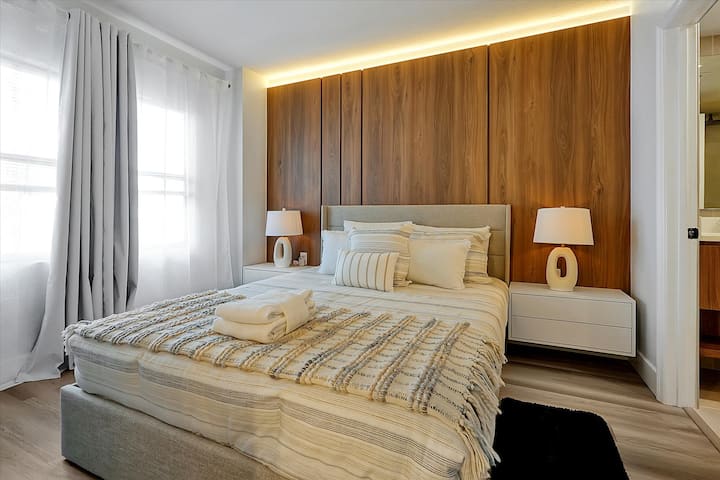 Chumba cha kulala chenye starehe chenye kitanda aina ya queen, mwanga laini na paneli maridadi za mbao.