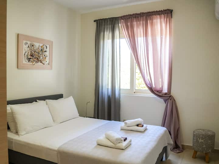 Um quarto lindamente decorado com uma confortável cama de casal, travesseiros macios e cortinas elegantes. Detalhes bem pensados e iluminação suave criam uma atmosfera tranquila e relaxante.
