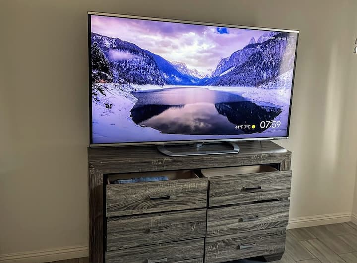 Smart TV postavljen na komodu s ladicama koja nudi dovoljno prostora za odlaganje. Uživajte u prirodnom svjetlu i slikovitom pogledu kroz veliki prozor s kojeg se pruža pogled na blistavi bazen u stražnjem dvorištu.