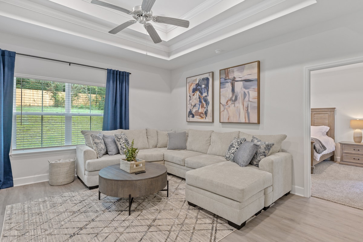 Sala de estar luminosa y acogedora con una decoración moderna, lujosos asientos y un gran televisor inteligente. Perfecto para relajarse después de un día de exploración de Tallahassee