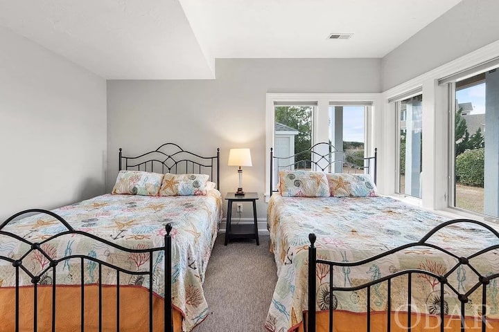 Large bedroom with two queen beds, two dressers, a closet and amoire, television with cable tv, adjacent bathroom with easy access to barcade and downstairs kitchenette. Windows all have draw-down shades. 