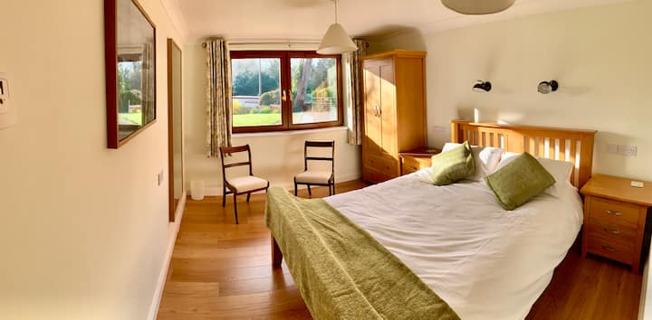 Cama tamaño king, mesitas de noche, sillas y armario, con ducha y baños adyacentes