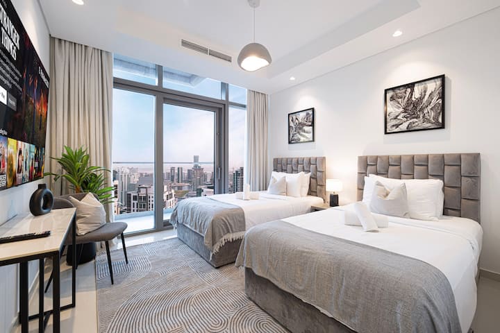 Ingia kwenye chumba cha kulala maridadi chenye vitanda viwili, matandiko bora kabisa. Sanaa hupamba kuta na dirisha kubwa hutoa mandhari ya kupendeza ya jiji. Palette maridadi huunda mandhari nzuri, ya kisasa.