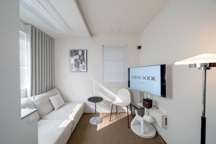 The second floor features a comfortable sofa bed alongside a painting by artist Lee Bae. It is also furnished with a Mudge’s Puppy Chair, a Samsung Smart TV, a Samsung air purifier, a Jackson Chameleon lamp, and a Ruark Audio R1.