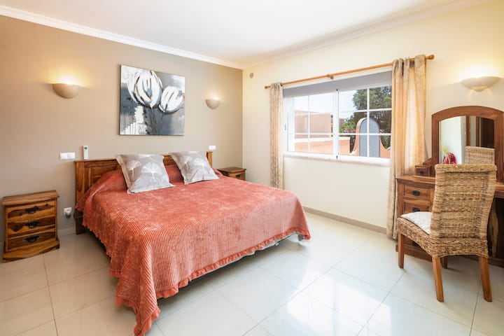 Спалня с голямо двойно легло на приземния етаж с врата към вътрешния двор, която води към терасата. 