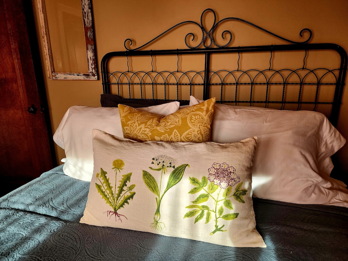 Crisp linens, plush pillows, and a vintage iron bed frame come together to offer a beautifully comfortable place to unwind.