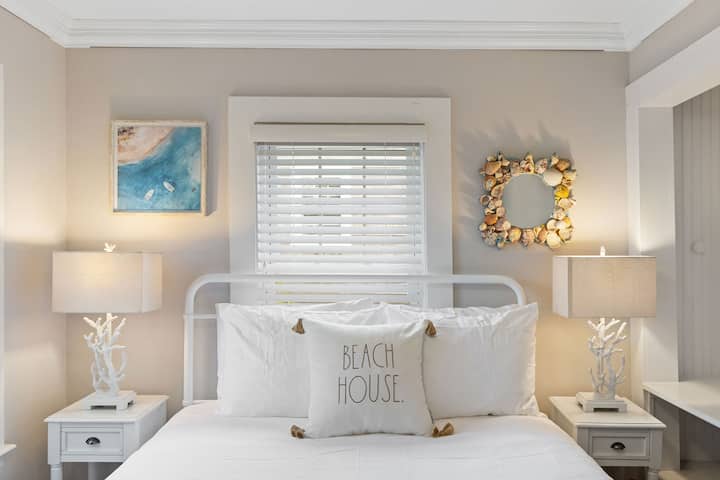 First floor bedroom with queen size bed, dresser, chair, and hotel quality linens. 