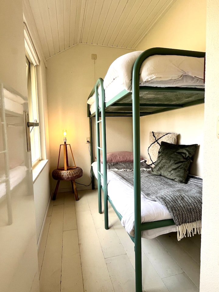 Slaapkamer 3 met stapelbed heeft een witte houten vloer en 190cm x 80cm bedden. Er komen nog extra plankjes en haakjes voor je kleding.