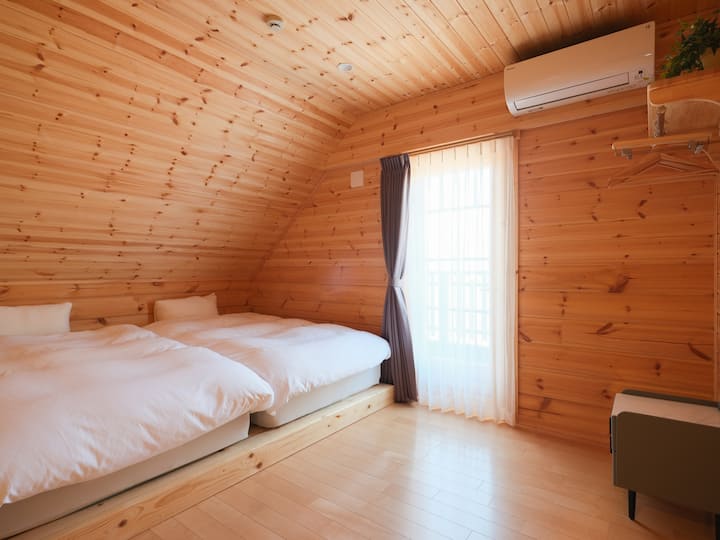 ベッド横にはハンガー用の木製棚が壁に設置されています。床は木目調で、空間に統一感があるベットルームです。