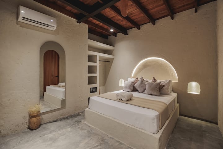 Las habitaciones de Villa La Santísima, con una cama tamaño queen y aire acondicionado, combinan un elegante estilo colonial con el lujo moderno, creando un ambiente sereno y refinado para la relajación.