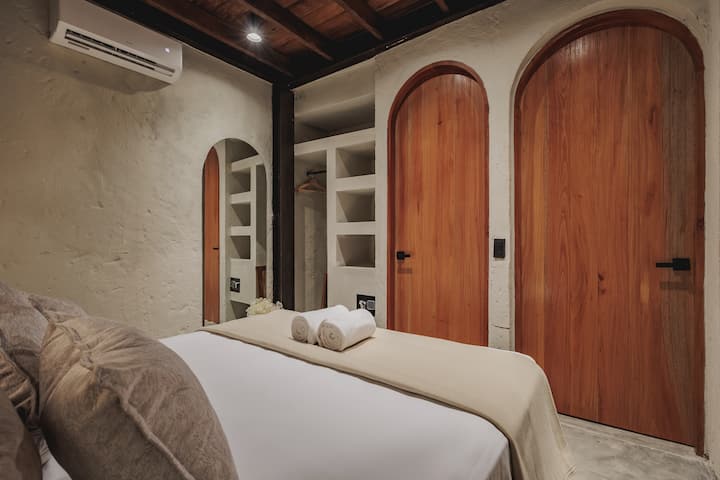 Las habitaciones de Villa La Santísima, con una cama tamaño queen y aire acondicionado, combinan un elegante estilo colonial con el lujo moderno, creando un ambiente sereno y refinado para la relajación.