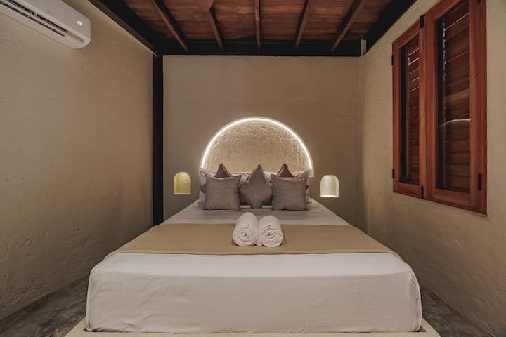 Las habitaciones de Villa La Santísima, con una cama tamaño queen y aire acondicionado, combinan un elegante estilo colonial con el lujo moderno, creando un ambiente sereno y refinado para la relajación.