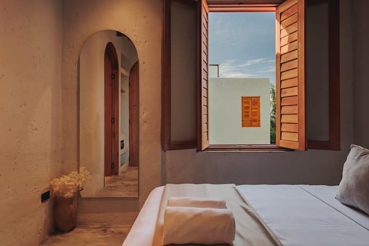 Las habitaciones de Villa La Santísima, con una cama tamaño queen y aire acondicionado, combinan un elegante estilo colonial con el lujo moderno, creando un ambiente sereno y refinado para la relajación.