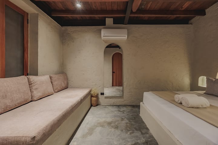 Las habitaciones de Villa La Santísima, con una cama tamaño queen y aire acondicionado, combinan un elegante estilo colonial con el lujo moderno, creando un ambiente sereno y refinado para la relajación.