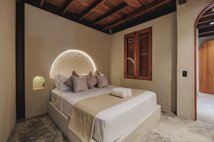 Las habitaciones de Villa La Santísima, con una cama tamaño queen y aire acondicionado, combinan un elegante estilo colonial con el lujo moderno, creando un ambiente sereno y refinado para la relajación.