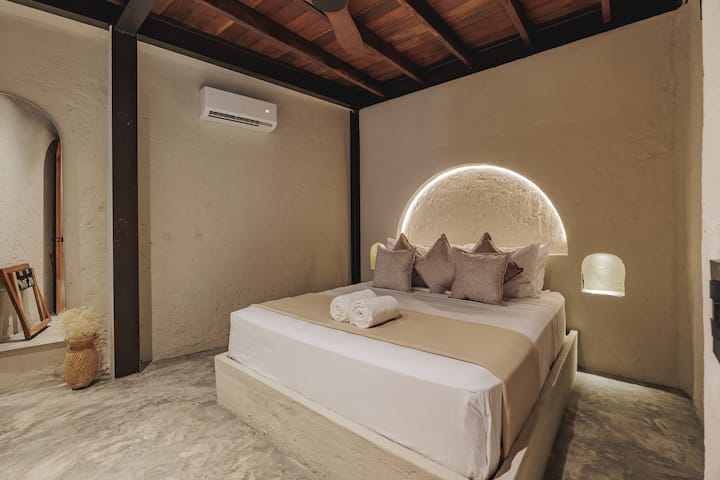 Las habitaciones de Villa La Santísima, con una cama tamaño queen y aire acondicionado, combinan un elegante estilo colonial con el lujo moderno, creando un ambiente sereno y refinado para la relajación.