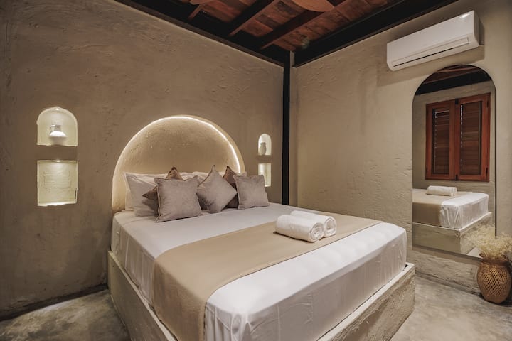 Las habitaciones de Villa La Santísima, con una cama tamaño queen y aire acondicionado, combinan un elegante estilo colonial con el lujo moderno, creando un ambiente sereno y refinado para la relajación.
