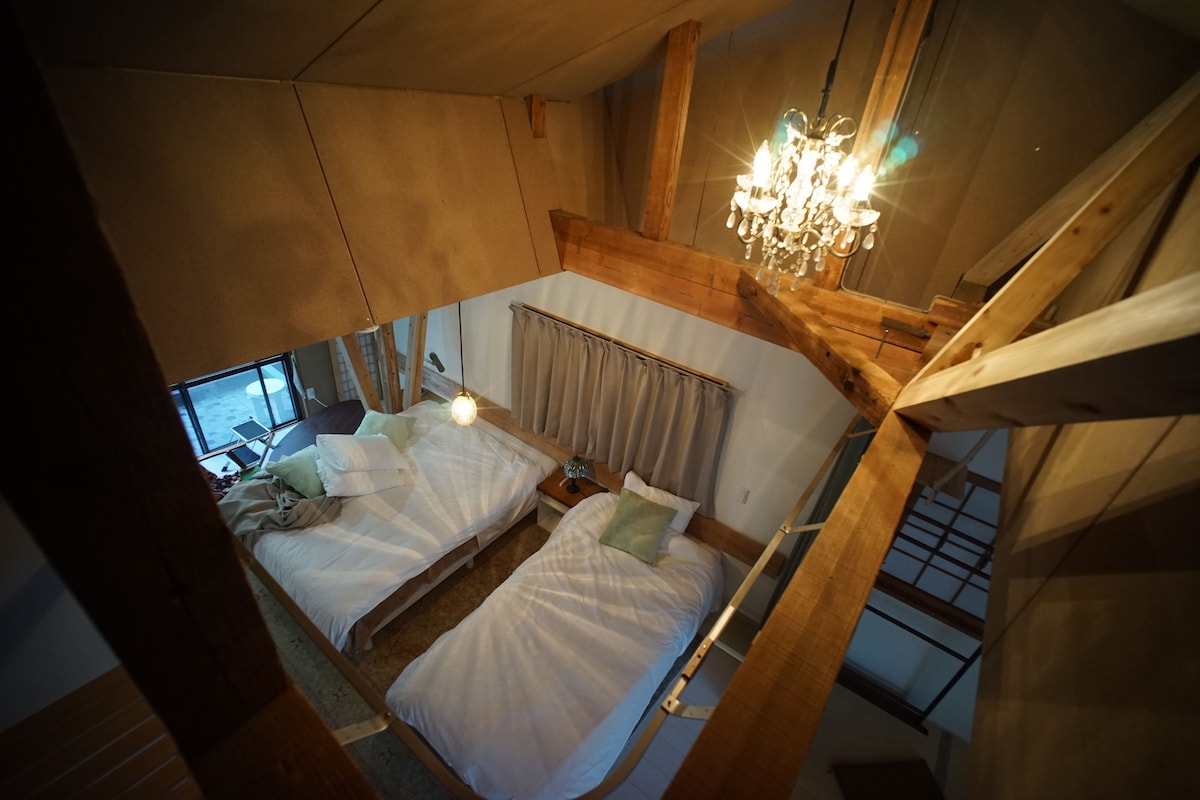 ２階中央に設けられているベッドスペースには、ダブルベッドとシングルベッドが置かれています。天井は高く屋根に設けたトップライトから光が柔らかに入ってきて、東西側の両テラスからの光も加えて、とても明るくかつ開放感に満ちた空間になっています。
ベッドスペースはカーテンでその他の部分と仕切れ、ゆったりとした時間を過ごすことができます。