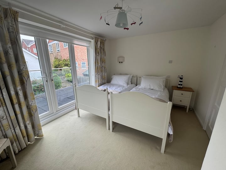 Bedroom Two with twin beds and glass doors leading to shared balcony. 