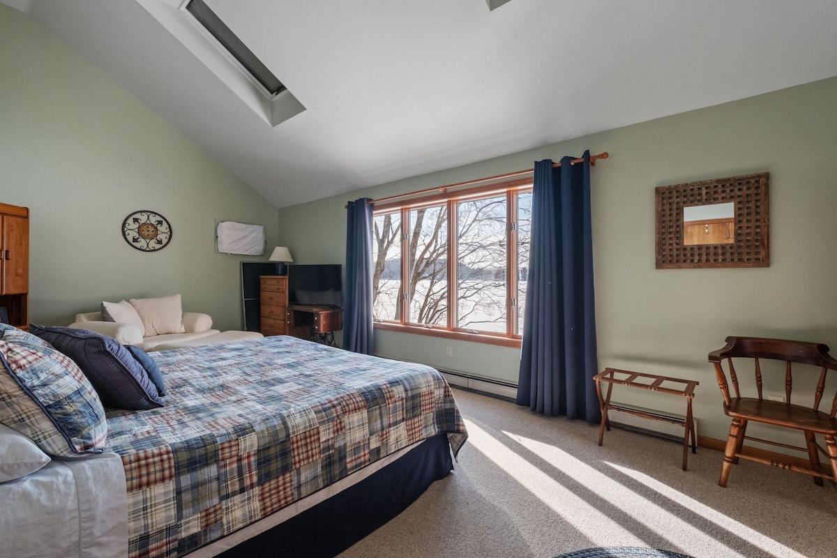 استيقظ على إطلالات هادئة على البحيرة وضوء الصباح في غرفة النوم الرئيسية المريحة هذه.