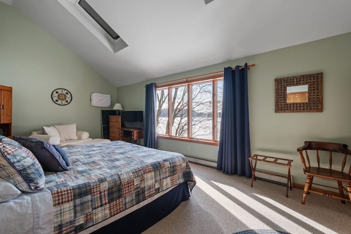 Zobuďte sa v tejto relaxačnej hlavnej spálni s pokojným výhľadom na jazero a ranným svetlom.