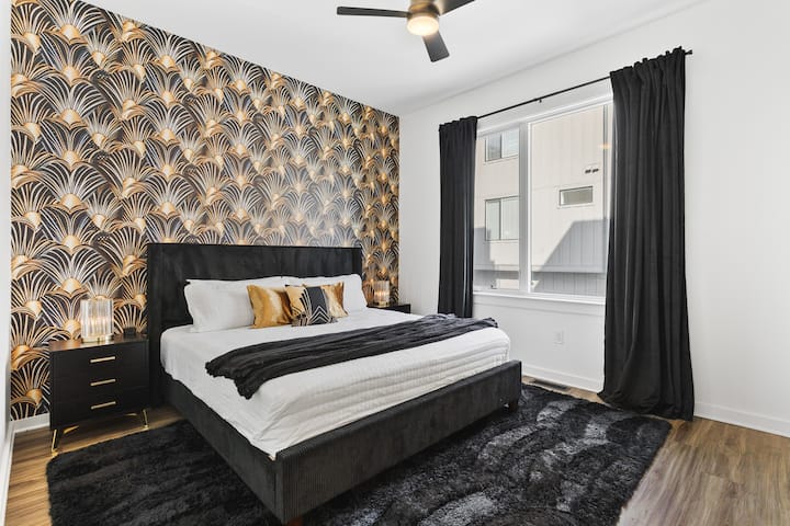 Chumba cha kulala cha msingi kilicho na kitanda cha kifalme, vivuli vya giza vya chumba, kabati, Televisheni mahiri na bafu la kujitegemea.