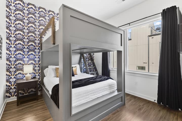 Malkia juu ya kitanda cha ghorofa cha malkia, vivuli vya giza vya chumba, kabati, televisheni mahiri na bafu lenye ukubwa kamili.