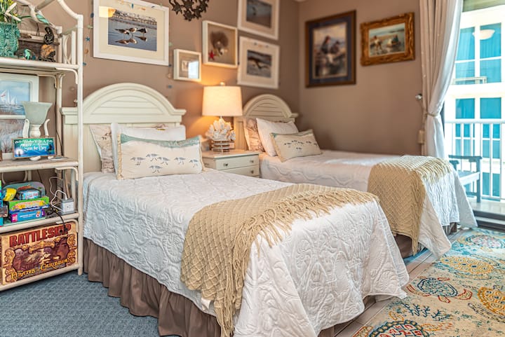 Dos acogedoras camas individuales vestidas con sábanas costeras crean el refugio perfecto para niños o amigos, con juegos y decoración junto al mar.