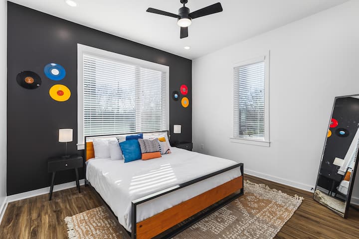 Unit #1: Bedroom #2 on the main level of the house, with a comfy king bed, ceiling fan, closet, full-length mirror and ensuite bathroom.