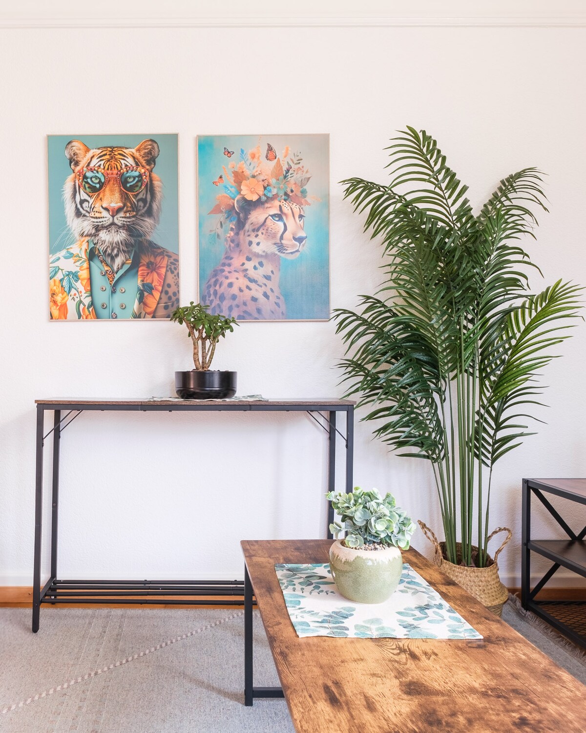 A stylish living area features two colorful art pieces of a fox and a cheetah. A tall green plant is displayed in the corner, alongside a console table and a wooden coffee table adorned with a potted succulent and a decorative bowl.