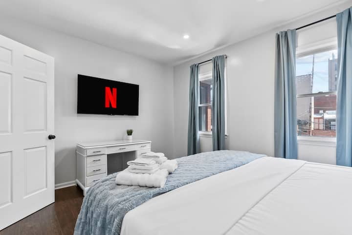 在这间宁静的加大双人床卧室中放松身心，配备柔和的蓝色装饰、毛绒床上用品和时尚的工作空间。 在55英寸智能电视上欣赏您最喜爱的节目，在专为舒适、宁静和安静的夜晚睡眠而设计的空间中放松身心。