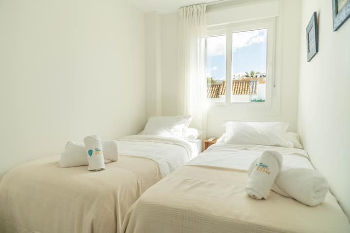 Dos camas individuales vestidas con textiles neutros y suaves, ideales para descansar tras un día de playa o aventura en Tarifa.