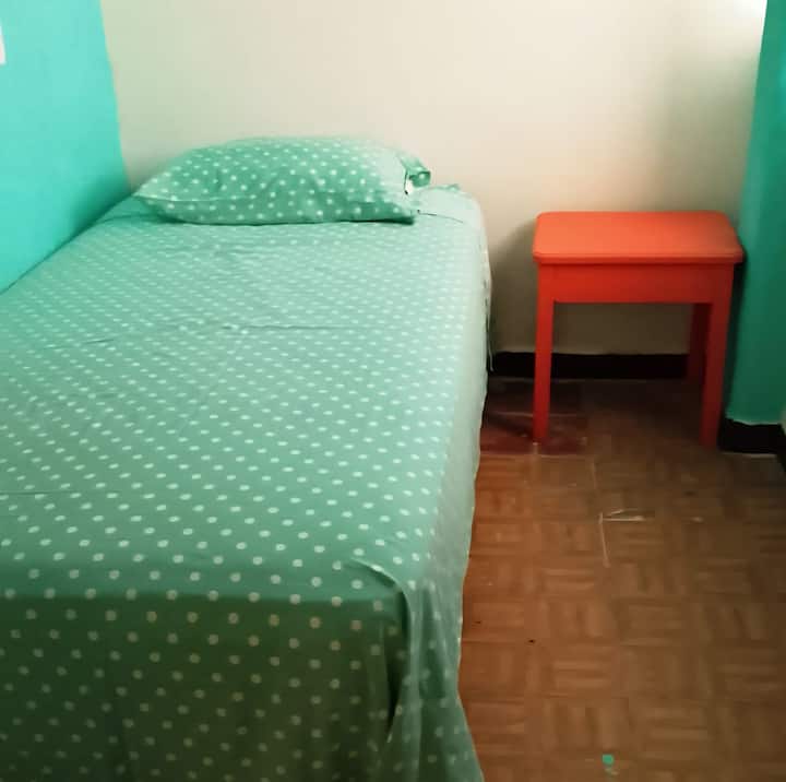 Ce lit individuel est dans une chambre privée à côté du salon et comprend une armoire pleine grandeur, une table d'appoint et une fenêtre donnant sur la rue avec une porte en bois insonorisée. C'est parfait pour le voyageur qui a besoin de la salle de bain au même étage.