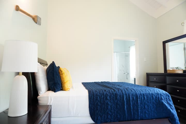 غرفة نوم بحري كوين مع حمام داخلي مع حوض استحمام.