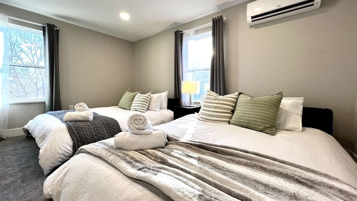 Queensize bedden met elk vier kussens en katoenen beddengoed. 