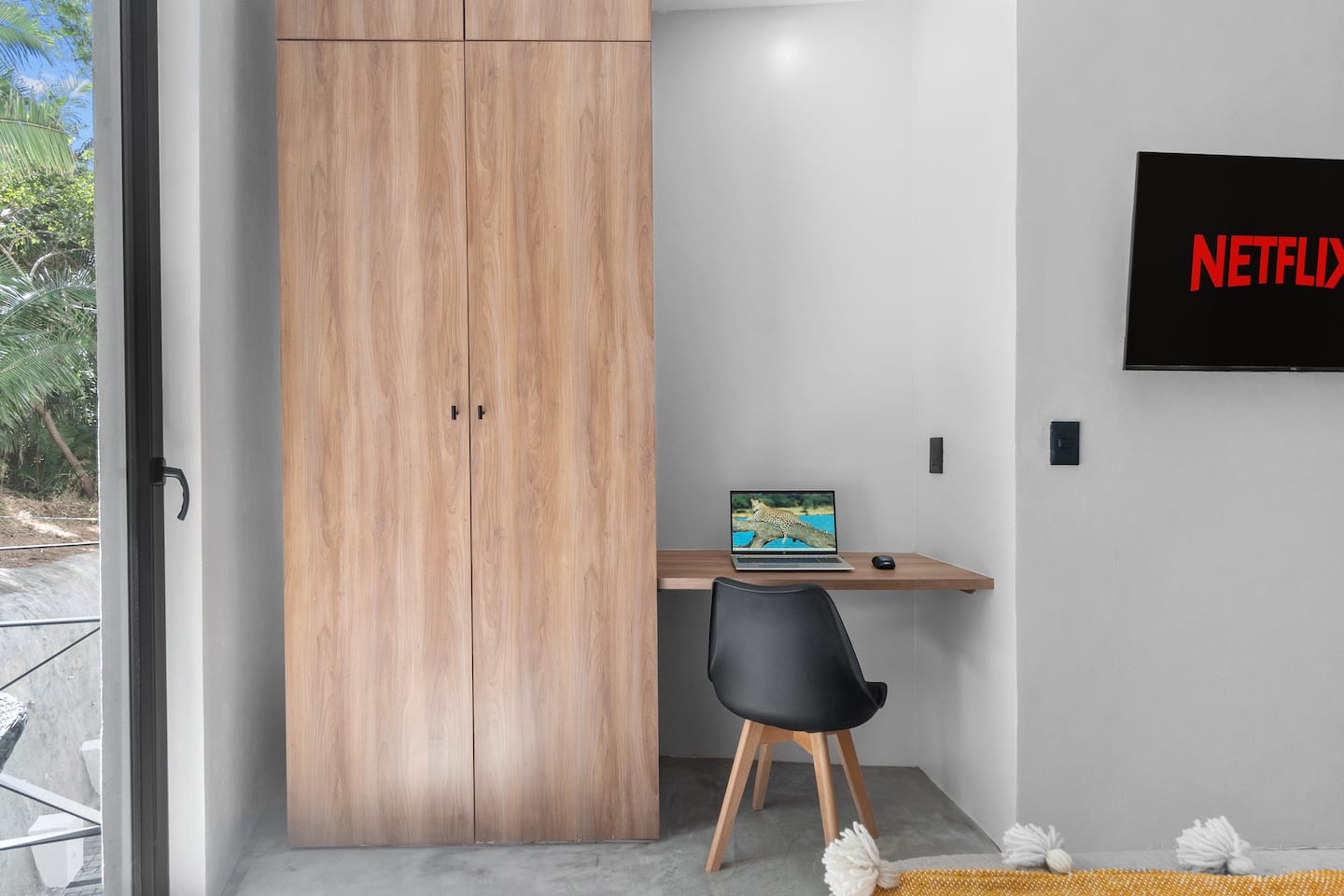 Your indoor workspace has a built-in wood desk, task chair, and full wardrobe beside it.