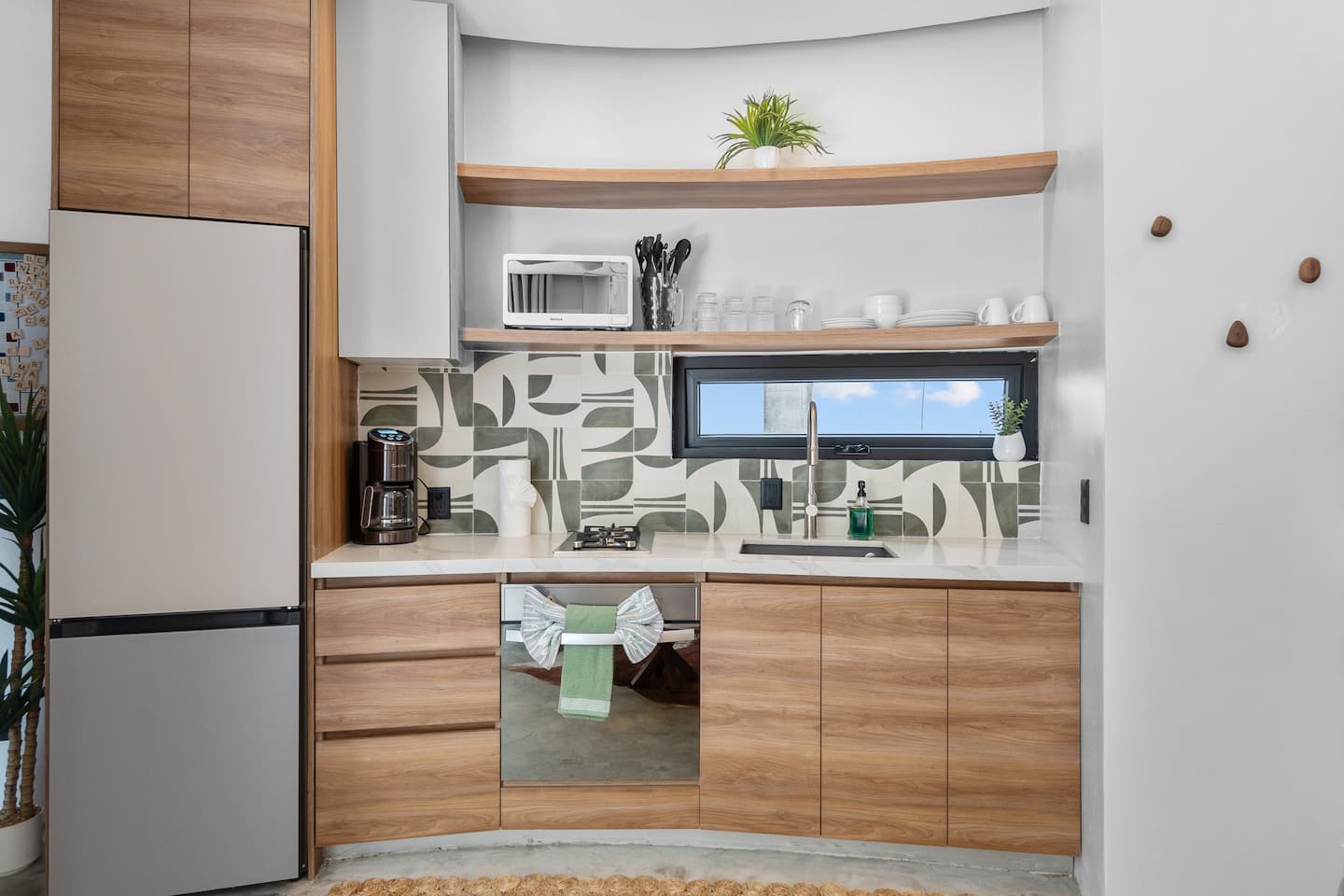 Cook your favorite meals in a fully stocked kitchen with wood cabinets, patterned tile backsplash, and everything you need already here.