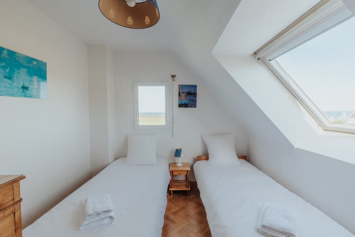 La chambre dispose de deux lits simples, et elle offre également une belle vue sur la mer grâce à la fenêtre de toit.