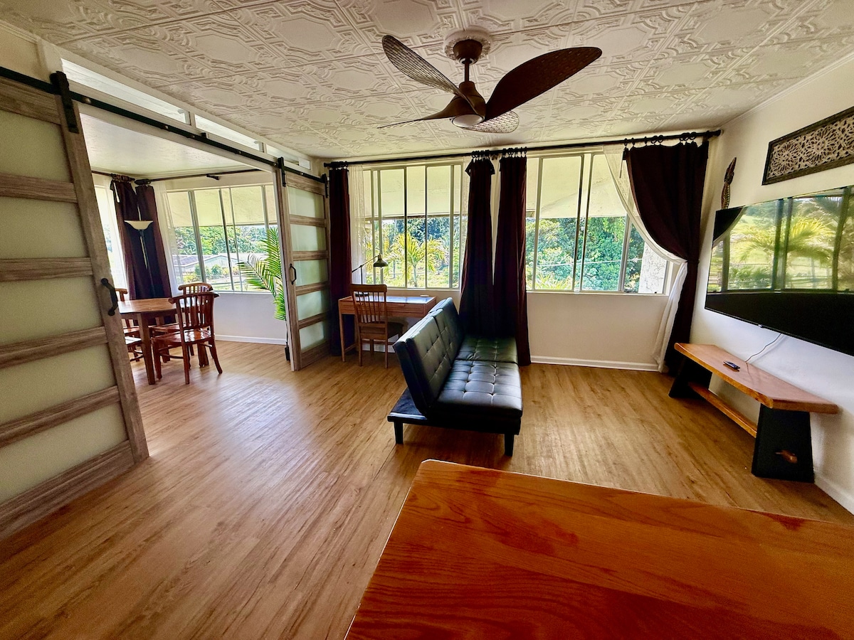 غرفة معيشة مع تلفزيون 70 بوصة ومساحة عمل مخصصة