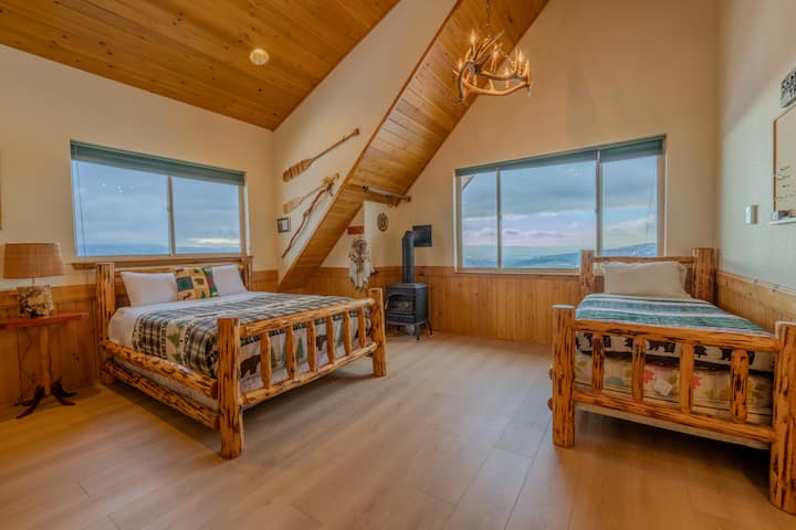 Спална соба на горниот кат со 1 брачен и 1 единечен кревет, сводести тавани и широк поглед кон долината подолу. Рустикалниот мебел од трупци, топлите дрвени акценти и удобниот шарм го прават мирно место за одмор по денот исполнет со планински авантури.