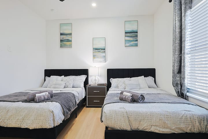 Tercer dormitorio diseñado con estilo y equipado con 2 camas de tamaño FULL, una  mesita de noche y un televisor inteligente de 50pulgadas.