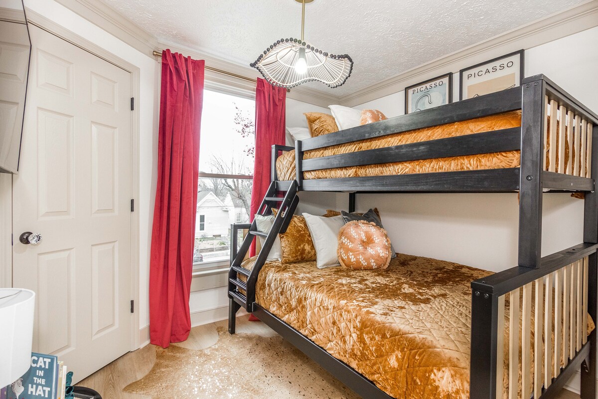 Пестене на място двуетажно легло с плюшено кехлибарено спално бельо и координиращи възглавници. Елегантната черна рамка контрастира красиво с топлите тонове, което прави това уютно кътче за спане идеално за деца или допълнителни гости.