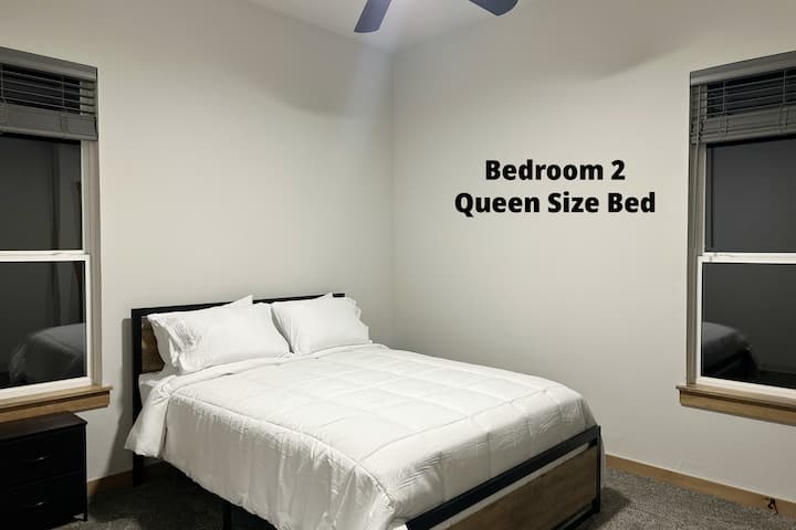 The bedroom in the far back to the left features a queen size bed, ceiling fan, and some books. Also has a closet for you to hang your clothes.
