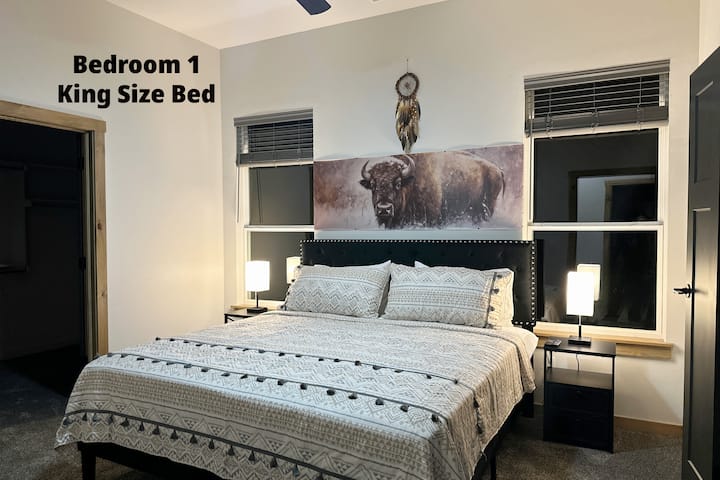 The master bedroom features a smart tv, ceiling fan, and some books. Also has a huge walk-in closet for you to hang your clothes, and luggage racks.